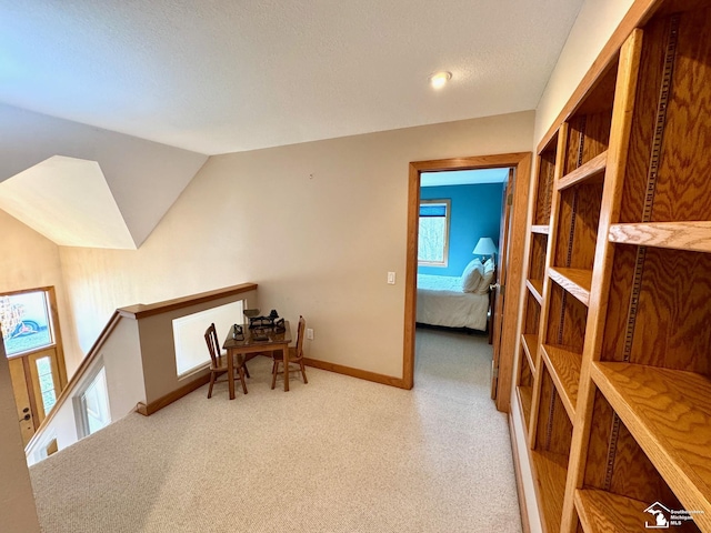 home office featuring light carpet, baseboards, vaulted ceiling, and a textured ceiling