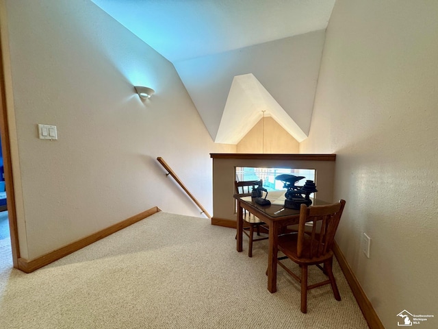 carpeted dining area with vaulted ceiling and baseboards