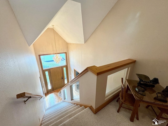 foyer entrance with stairs, high vaulted ceiling, carpet, and an inviting chandelier