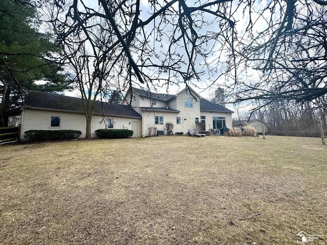 back of house featuring a chimney and a lawn