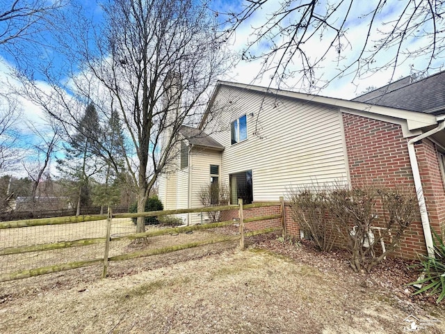 view of property exterior featuring brick siding and fence