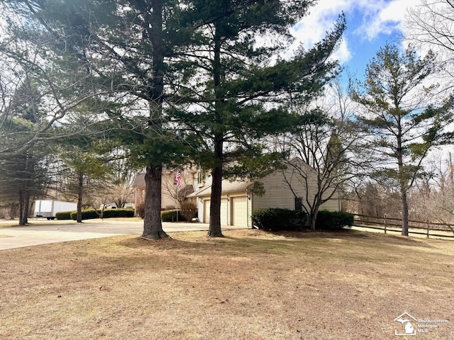 view of yard with driveway, an attached garage, and fence