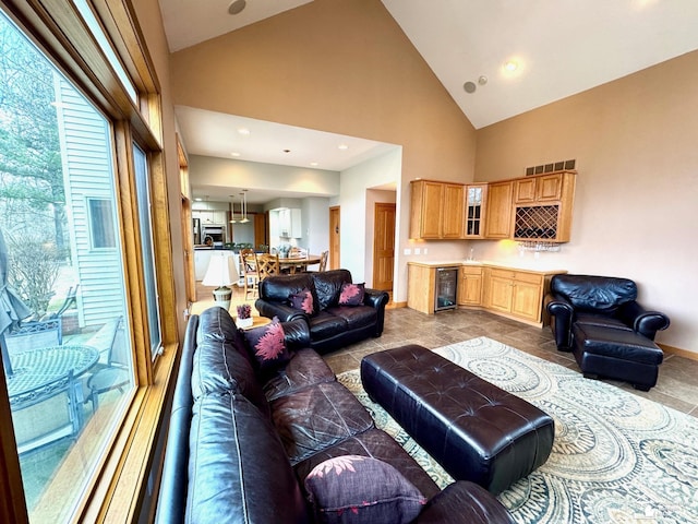 living area featuring high vaulted ceiling, wine cooler, bar, and baseboards