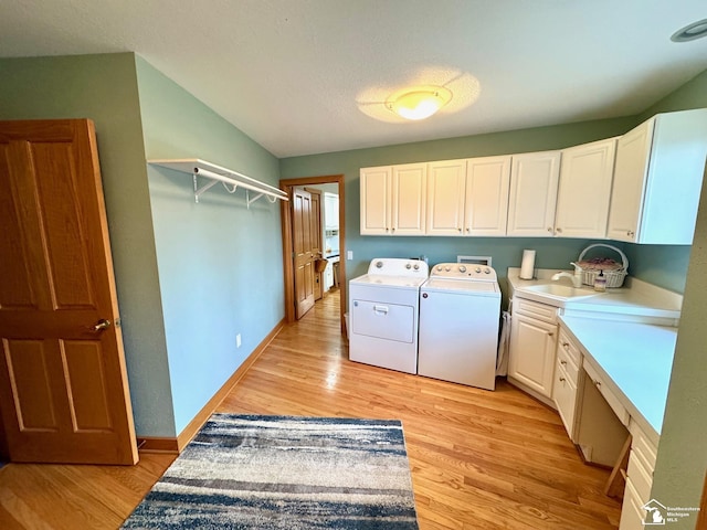 washroom with cabinet space, light wood-style floors, a sink, separate washer and dryer, and baseboards