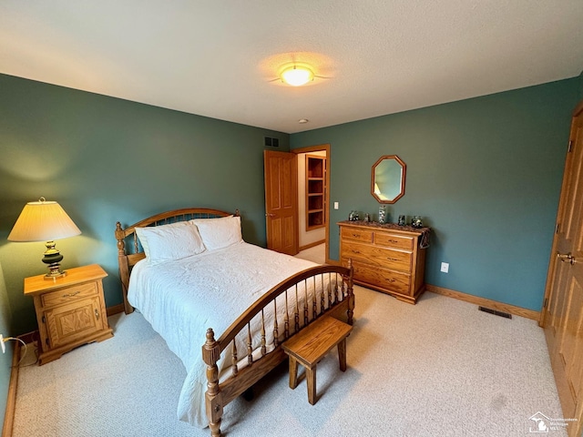 bedroom featuring light colored carpet, visible vents, a textured ceiling, and baseboards