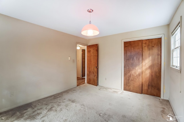 unfurnished bedroom with a closet, carpet flooring, and baseboards