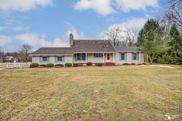 ranch-style home featuring brick siding, a chimney, a front yard, and fence