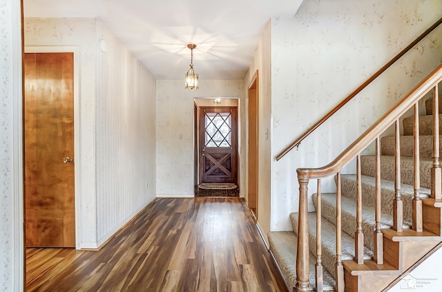 foyer with stairs, wallpapered walls, baseboards, and wood finished floors