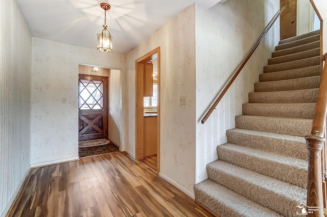 foyer featuring stairs, wood finished floors, baseboards, and wallpapered walls