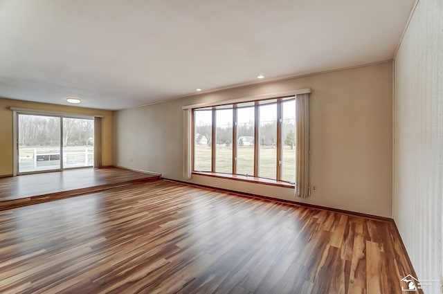 unfurnished room featuring a wealth of natural light, baseboards, wood finished floors, and recessed lighting