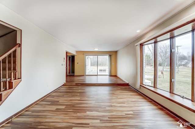 unfurnished room with light wood finished floors, stairway, and baseboards