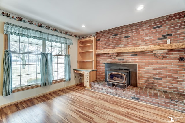 unfurnished living room with light wood-style floors, recessed lighting, a wood stove, and baseboards