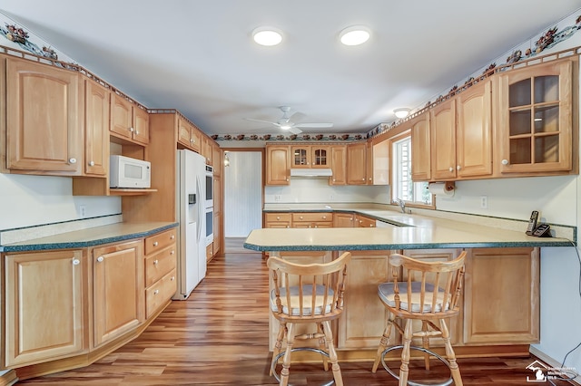 kitchen with white appliances, glass insert cabinets, a peninsula, light wood-type flooring, and a sink