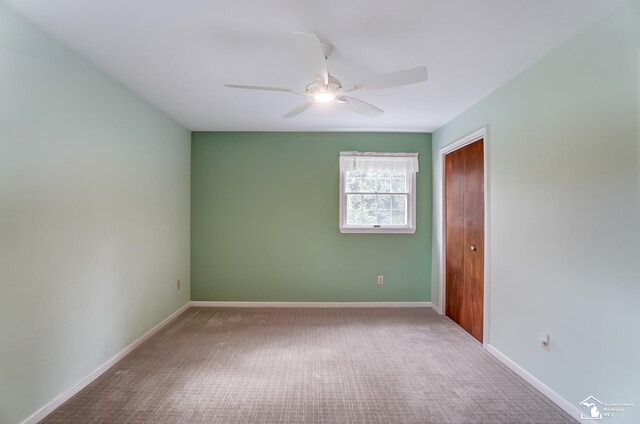 carpeted spare room with ceiling fan and baseboards