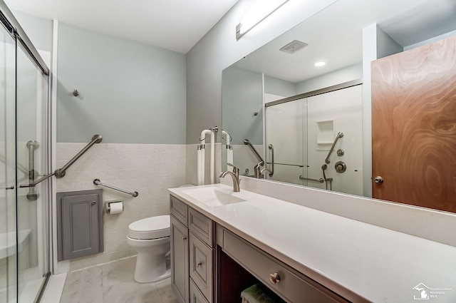 bathroom featuring a wainscoted wall, tile walls, a shower stall, and vanity