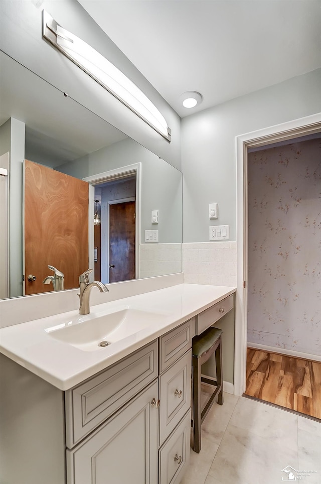 bathroom with a wainscoted wall, tile patterned flooring, tile walls, and vanity