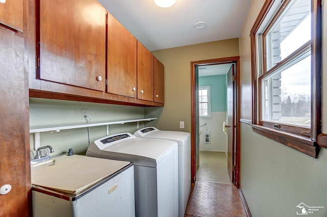 clothes washing area with separate washer and dryer, a sink, and cabinet space