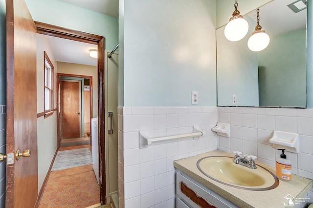 bathroom with a wainscoted wall, walk in shower, vanity, and tile walls