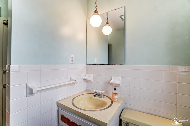 bathroom featuring toilet, wainscoting, tile walls, and vanity