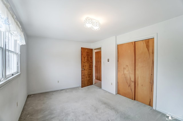 unfurnished bedroom featuring light carpet and a closet