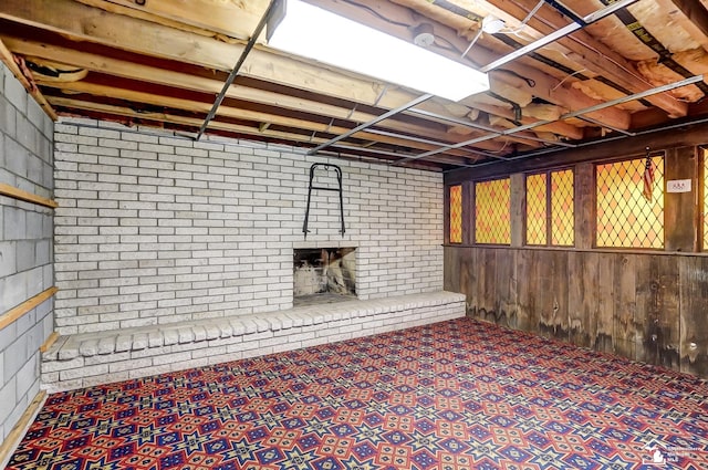 finished below grade area featuring carpet floors, a brick fireplace, and wood walls