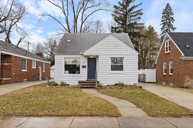 bungalow-style house featuring a front yard, roof with shingles, and fence