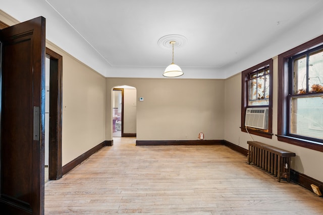 2412 Cornell St, Dearborn, MI 48124 - empty room featuring arched walkways, baseboards, light wood finished floors, and radiator heating unit