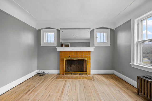 2412 Cornell St, Dearborn, MI 48124 - unfurnished living room featuring baseboards, a tile fireplace, hardwood / wood-style flooring, and radiator