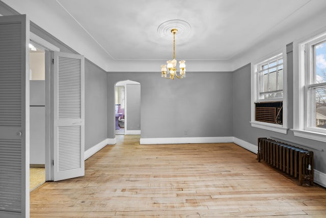 2412 Cornell St, Dearborn, MI 48124 - unfurnished dining area featuring arched walkways, a chandelier, wood finished floors, baseboards, and radiator