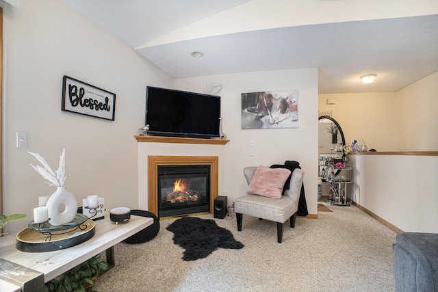 living area with a glass covered fireplace, carpet flooring, vaulted ceiling, and baseboards