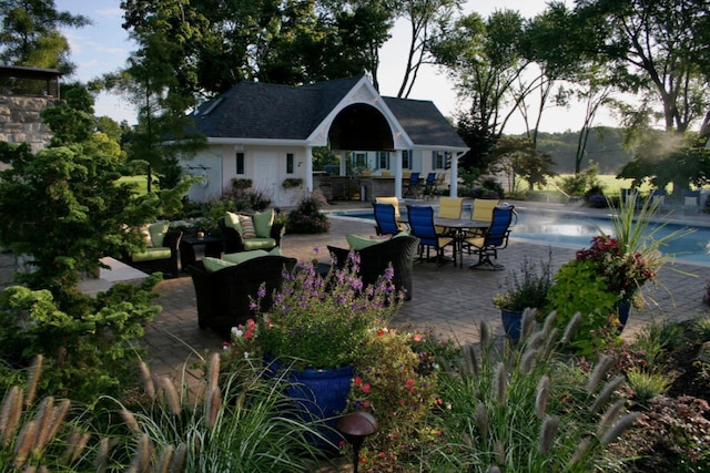 exterior space with a patio, an outdoor hangout area, an outbuilding, a storage structure, and a pool