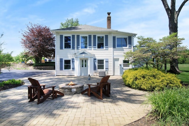 exterior space with cooling unit, an outdoor fire pit, a patio area, and a chimney