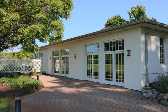 exterior space featuring french doors, a patio area, fence, and stucco siding