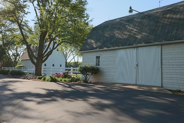 view of side of property featuring roof with shingles and fence