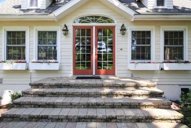 view of exterior entry with roof with shingles