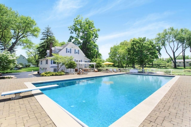 view of swimming pool featuring a diving board, a patio area, fence, and a fenced in pool