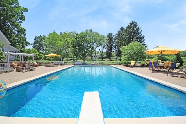 outdoor pool with a patio area and a diving board