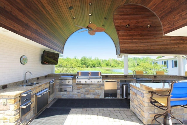 view of patio featuring ceiling fan, exterior kitchen, area for grilling, and a sink