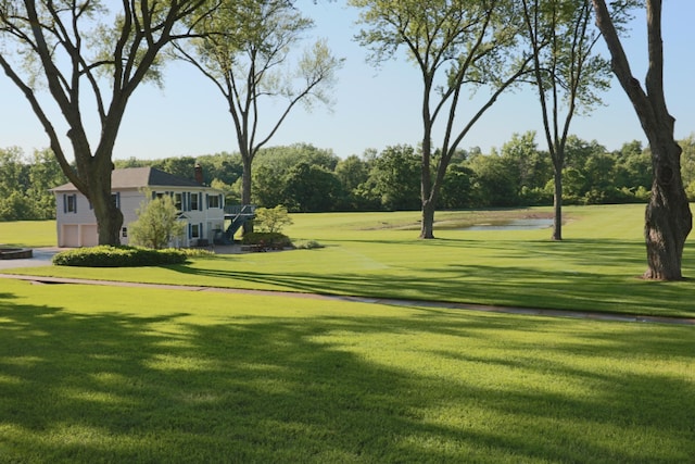 view of home's community with a lawn, an attached garage, and a water view