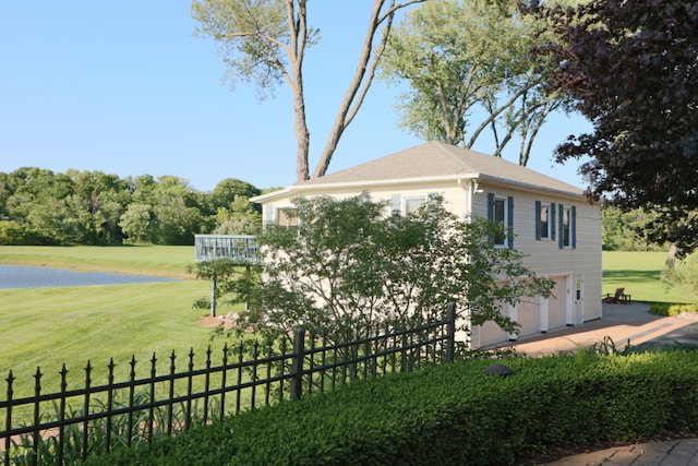 view of home's exterior with driveway, an attached garage, fence, and a lawn