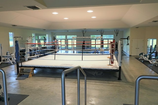 exercise room with a raised ceiling, visible vents, and recessed lighting