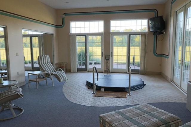 interior space with french doors, a towering ceiling, and baseboards