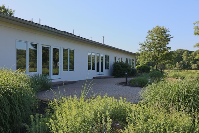 rear view of property with a patio and stucco siding