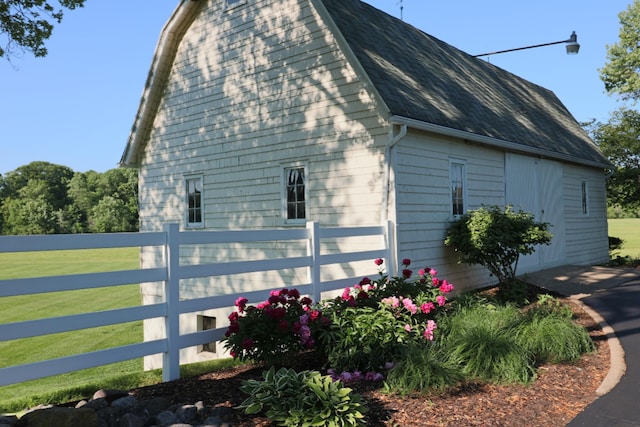 view of home's exterior with a shingled roof, a lawn, and fence