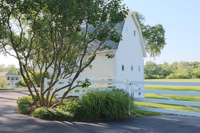 view of property exterior with roof with shingles, fence, and a gambrel roof