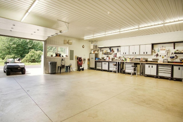 garage with electric panel, water heater, metal wall, and a workshop area