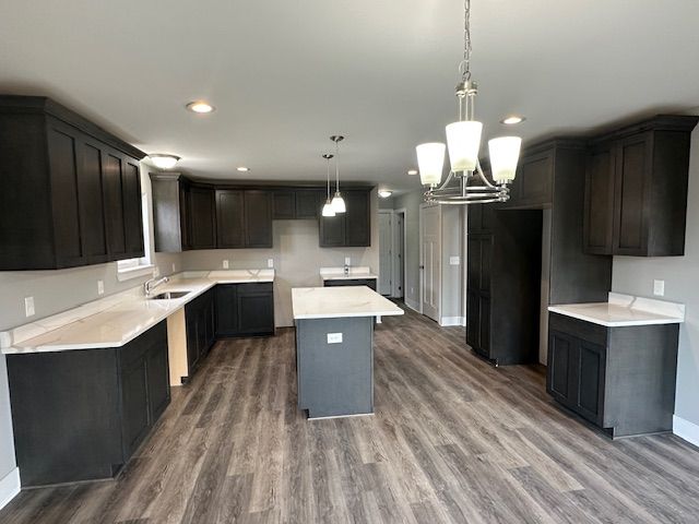 kitchen with wood finished floors, recessed lighting, a sink, and a center island