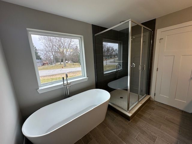 bathroom featuring a stall shower, wood tiled floor, and a freestanding tub