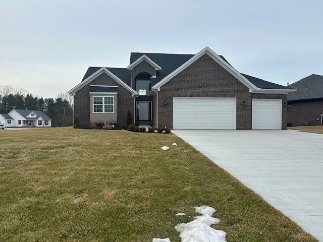 view of front of house with a garage, a front yard, brick siding, and driveway