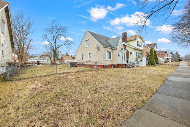 view of home's exterior featuring a yard, a chimney, entry steps, fence, and a residential view